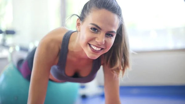 Smiling woman exercising on a fitness ball in a gym