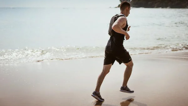 Man running along the beach at the water's edge