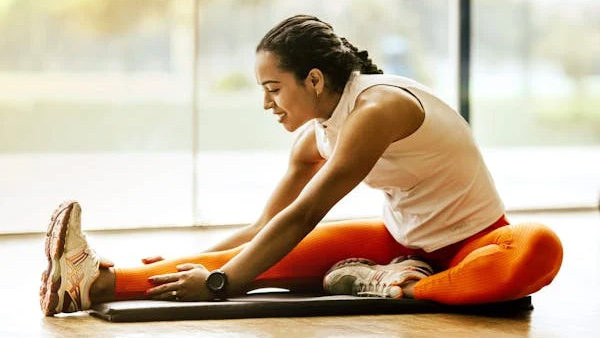 Woman on an exercise mat stretching forward to her toes