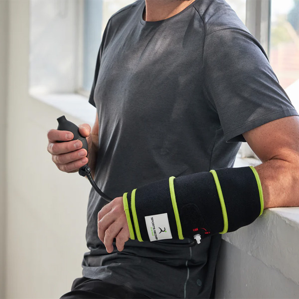 Man with a black compression wrap on his forearm, holding a hand pump